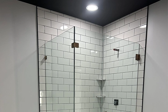 Corner shower with glass panels and subway tile walls.
