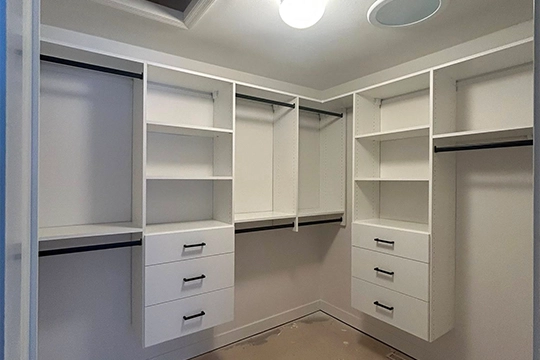 Empty white custom closet with shelving and drawers.