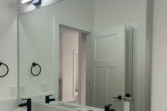 Large bathroom mirror above a white sink with black fixtures.