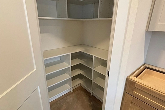 white custom corner closet with multiple shelves and beige carpet floor