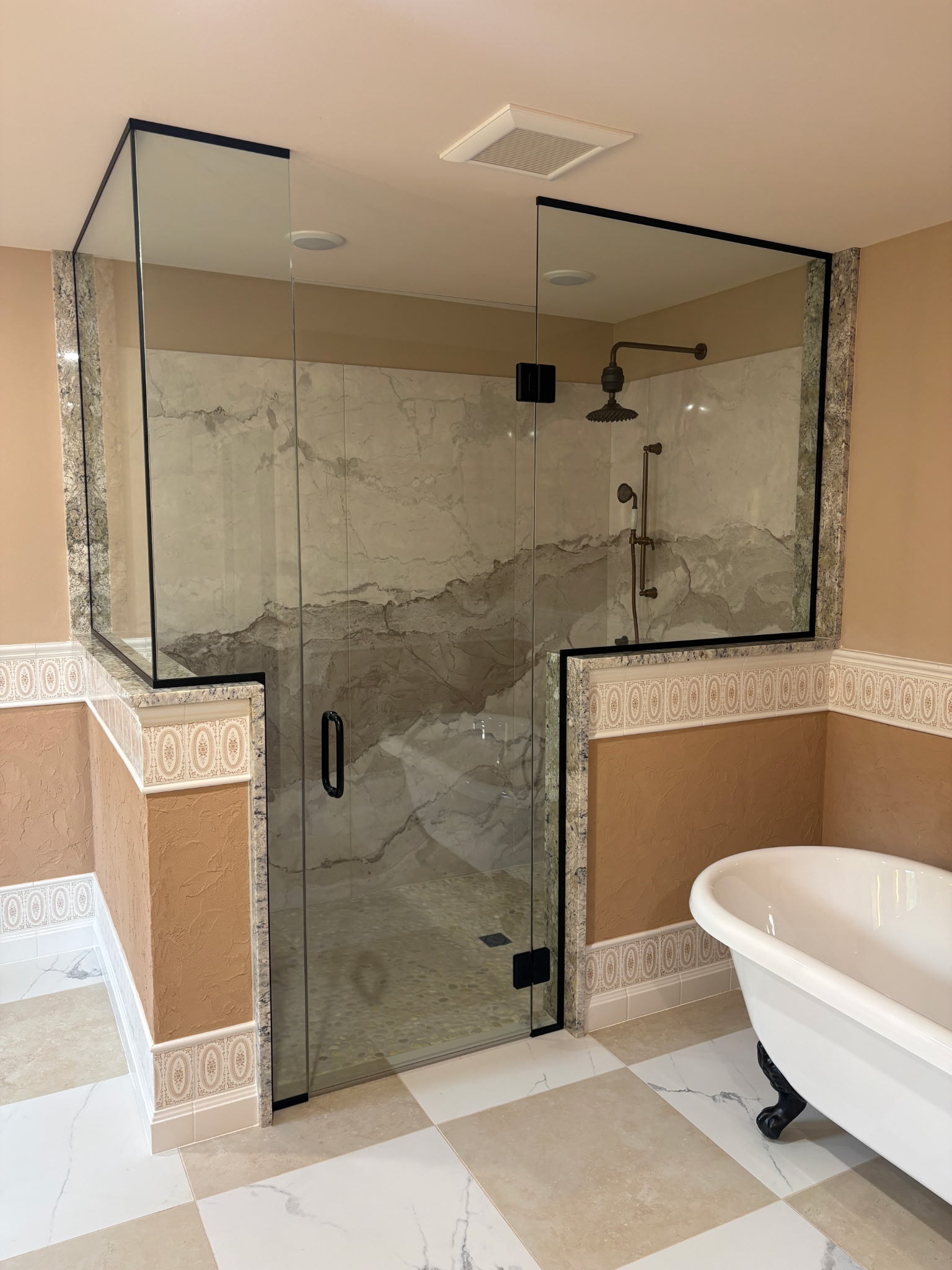 Frameless glass shower enclosure in a modern bathroom with a clawfoot tub.